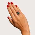 Zahra 18K gold ring worn on a hand, with a rectangular green tourmaline centre surrounded by pink rhodolite garnets.