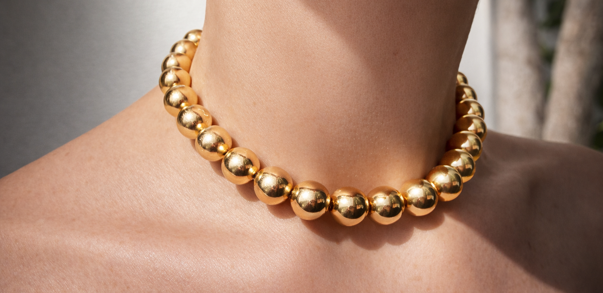 Sofia gold bead necklace worn around the neck, with polished spherical beads catching the light.