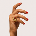 Buzz 18K gold bumblebee ring worn on a hand with red nails, showing a red gemstone body above a wide polished band.