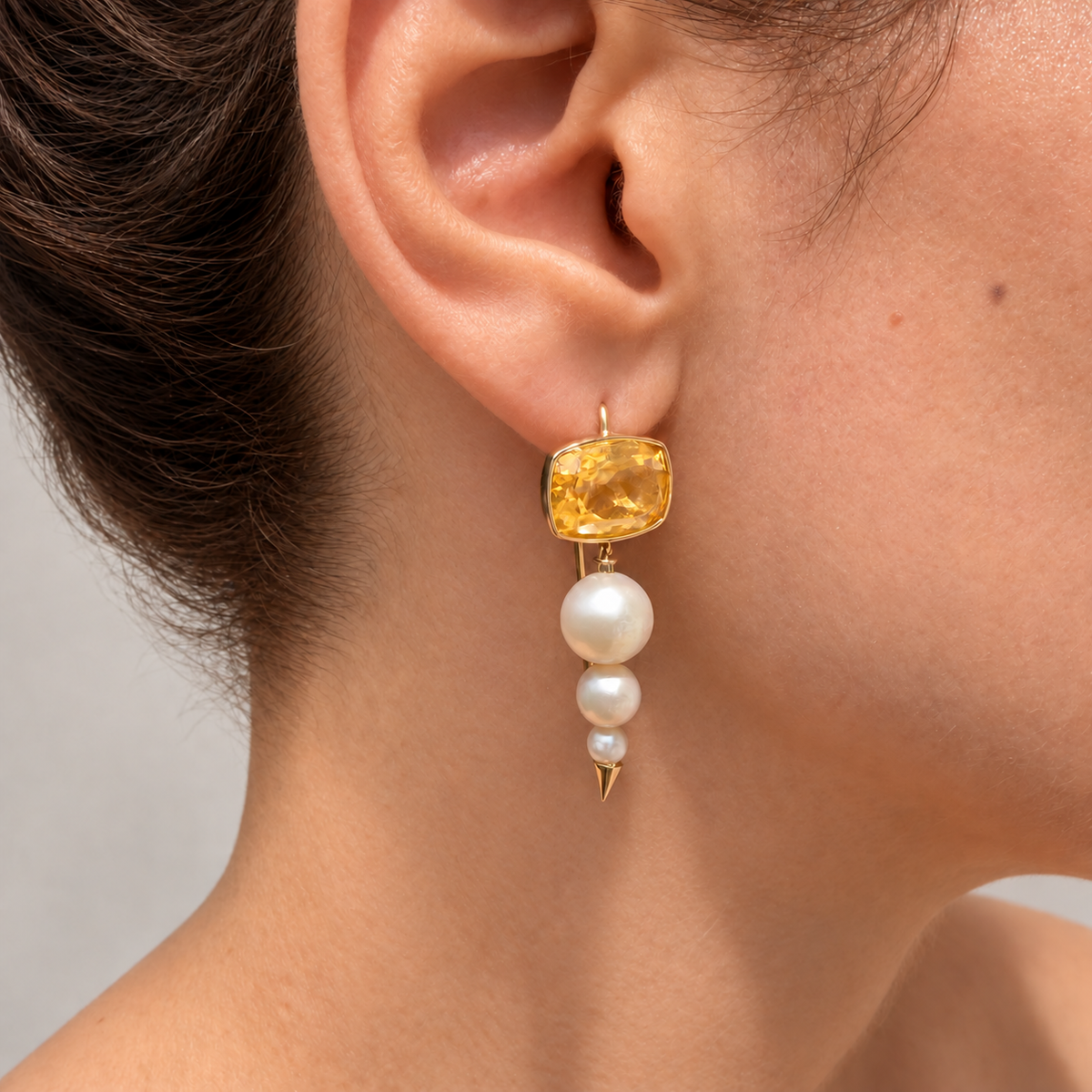 Short Anoud citrine and three-pearl drop earring in 18K gold, shown worn on the ear.
