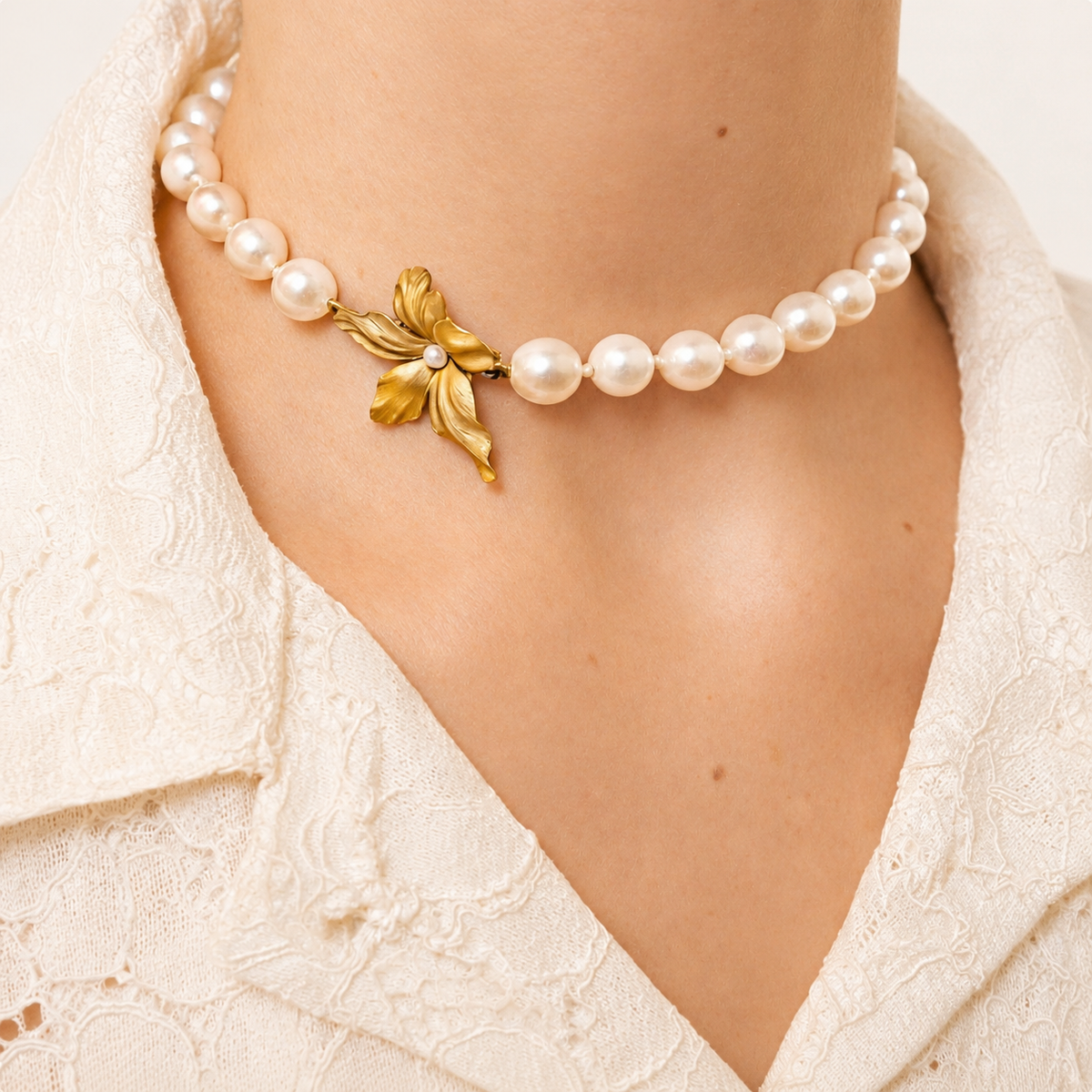 Beatrice freshwater pearl choker worn at the neck, with a sculpted 18K gold flower and pearl centre above a white lace collar.