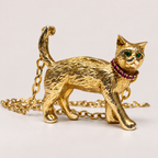 Side view of the Charlie 18K gold cat pendant, showing textured fur, emerald eyes, a ruby collar and raised tail.