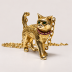 Charlie cat pendant in textured 18K gold, shown from the front with emerald eyes, a ruby collar and a raised tail.