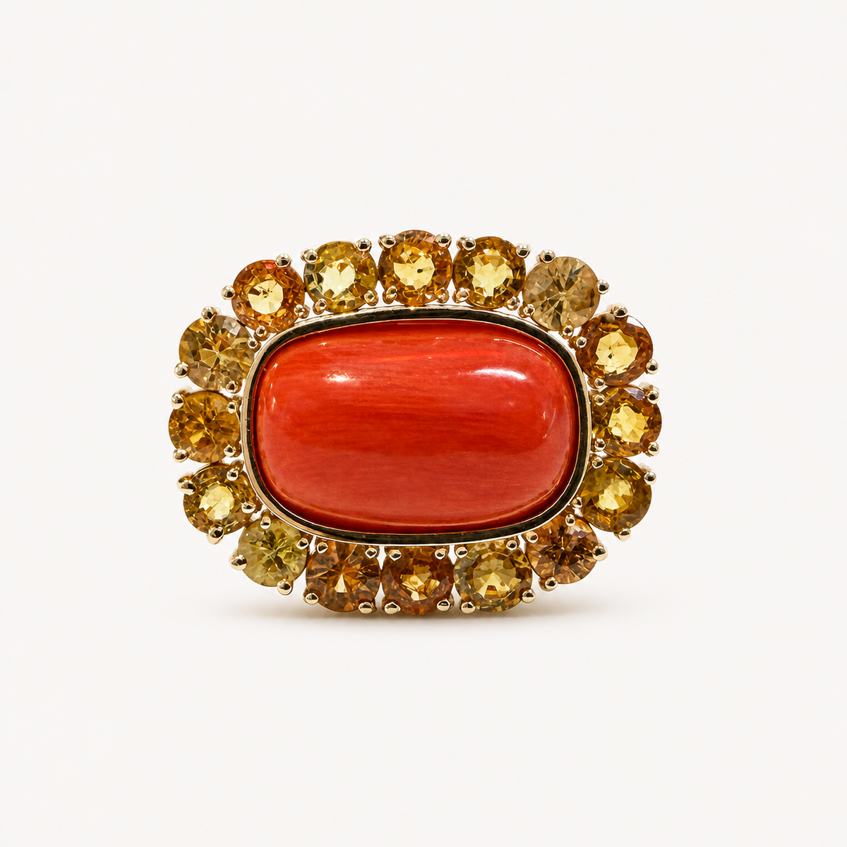 Front view of the Coralie 18K gold ring, with a smooth red Italian coral cabochon framed by round golden sapphires.