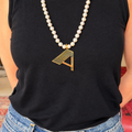 Gold Deco initial A pendant on a freshwater pearl necklace, worn over a black sleeveless top.