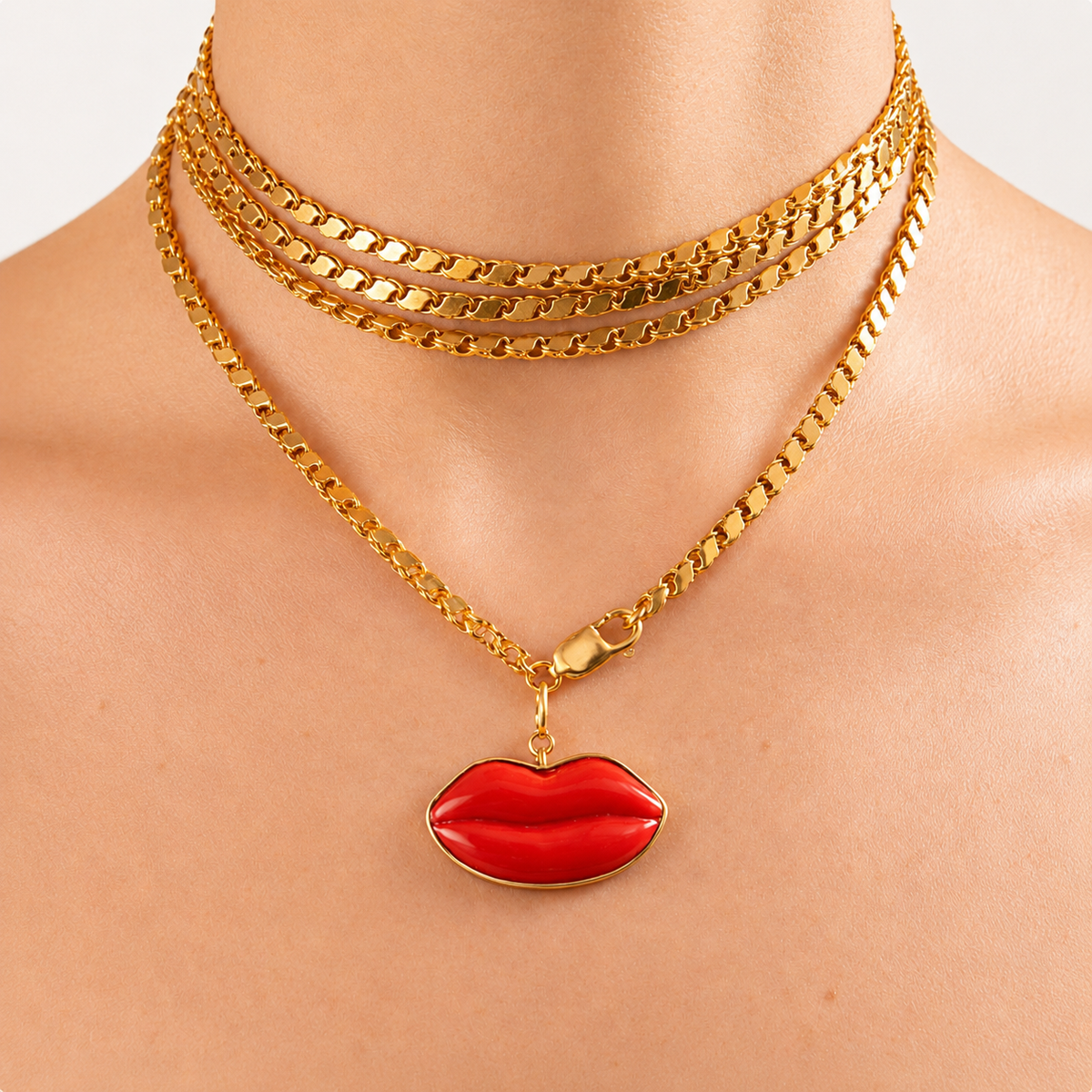 Dina red coral lips pendant framed in 18K gold, worn on a gold chain layered around the neck.