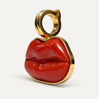 Angled view of the Dina red coral lips pendant, showing its sculpted surface, 18K gold rim and circular hinged bail.