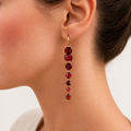 Dominique garnet drop earring worn on a model, with a long line of deep red gemstones suspended from a small gold hoop.