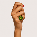 Fleur 18K gold cluster ring worn on a hand, with a bright green peridot centre surrounded by darker chrome diopside stones.
