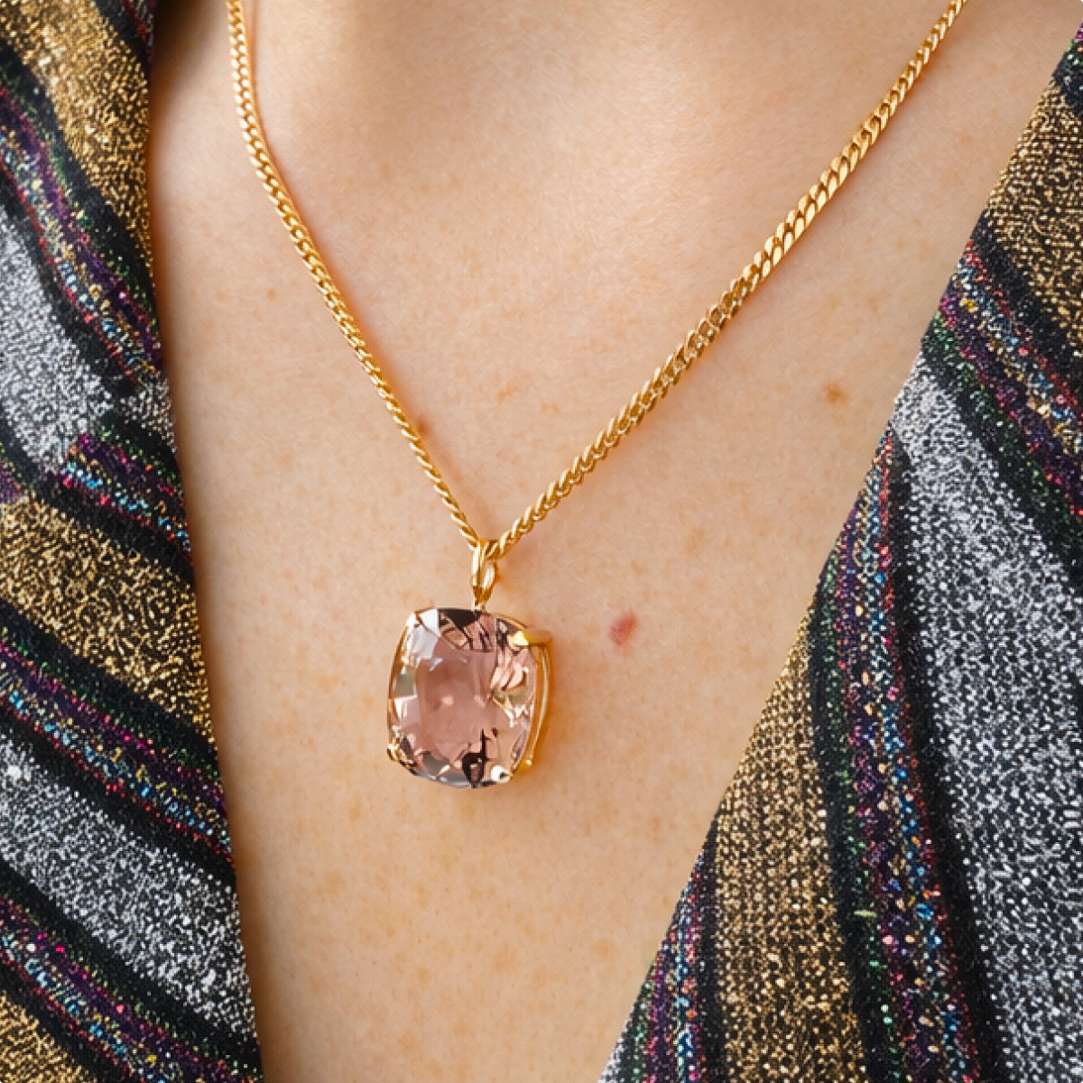 Pale lilac cushion-cut ametrine charm worn on a fine gold chain above a multicoloured patterned neckline.