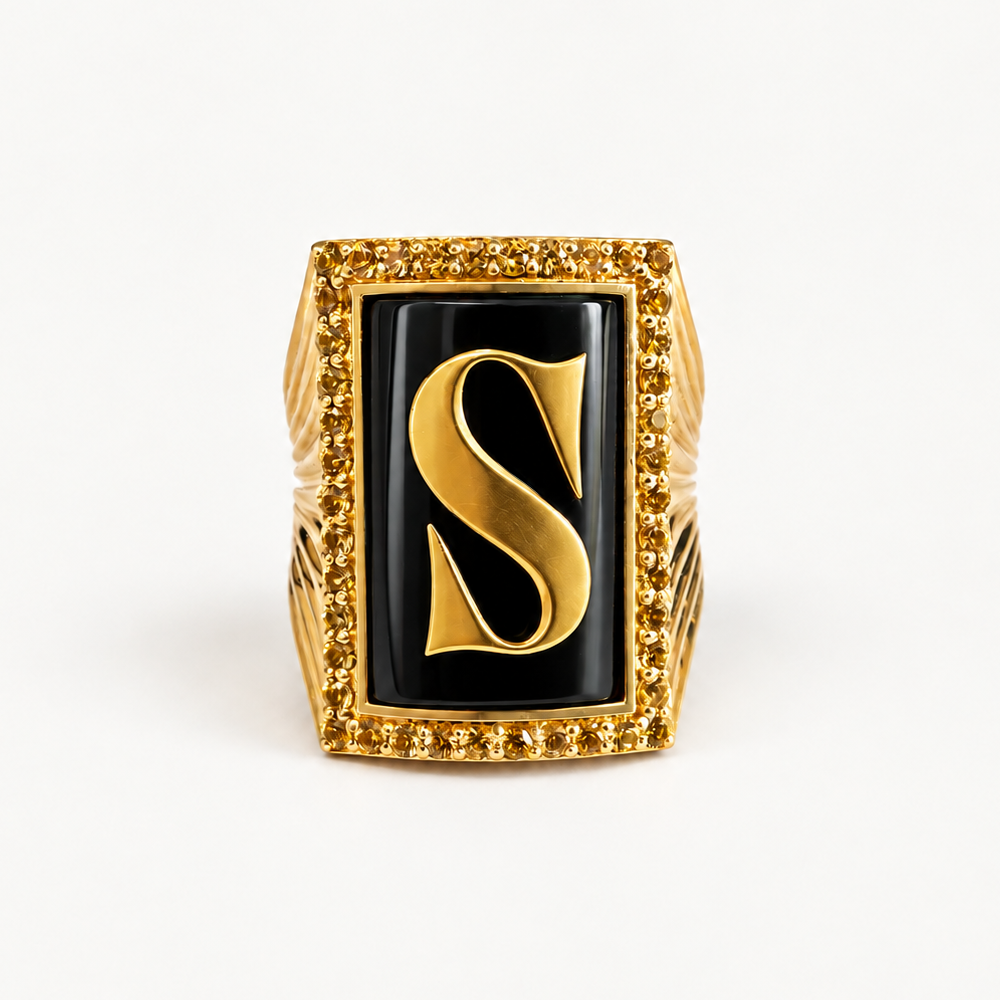 Front view of the 18K gold initial S ring with black onyx and a golden sapphire halo.
