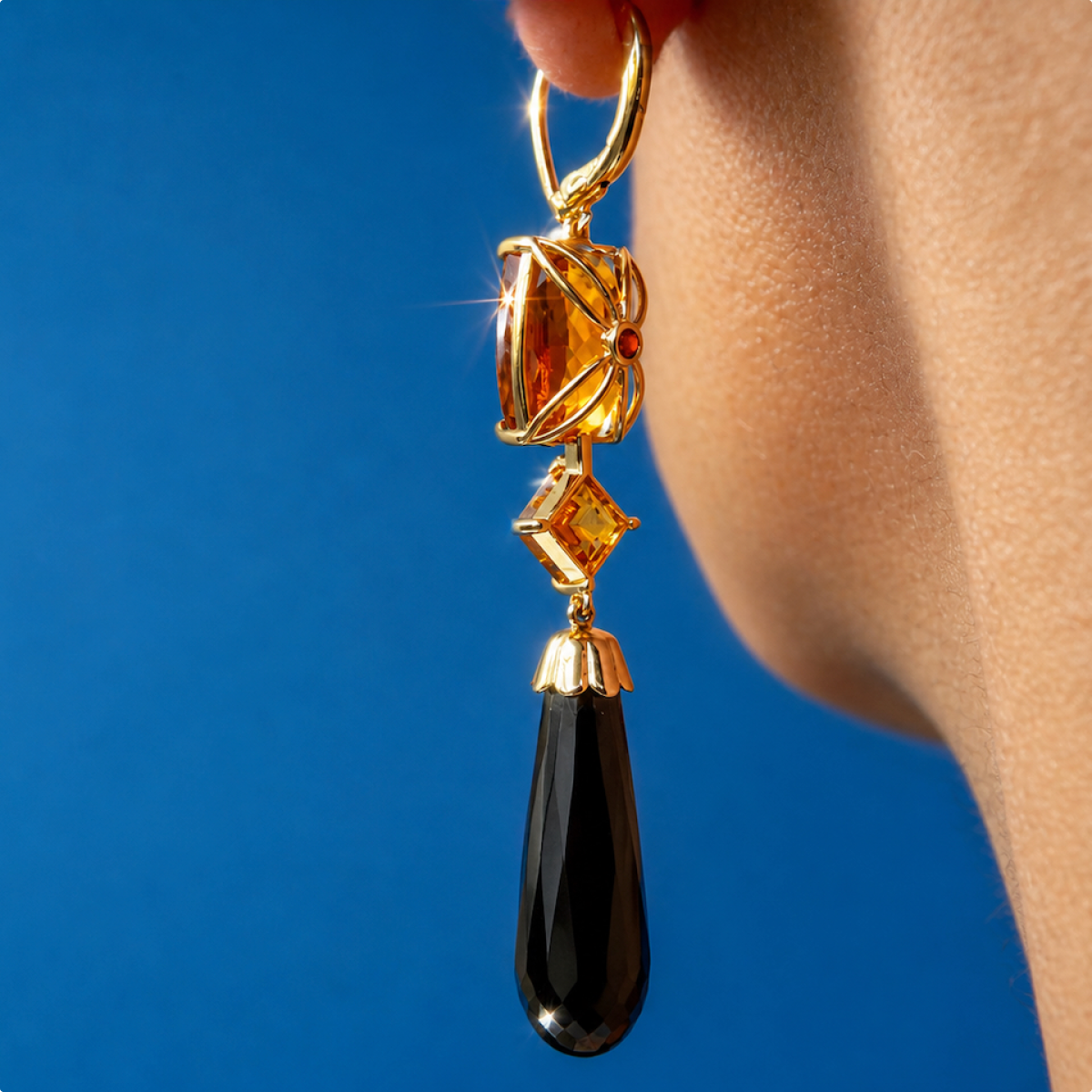 Side close-up of the Lara earring worn at the ear, showing the floral gold citrine setting and faceted black onyx drop.