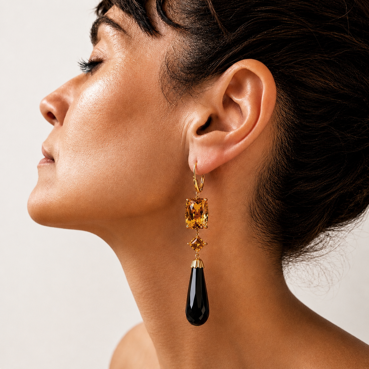 Lara 18K gold earring worn on a model, with golden citrines above a long faceted black onyx teardrop.