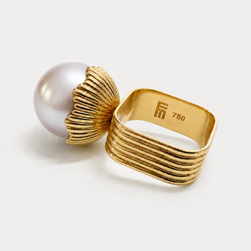 Side view of the Loulou pearl ring, showing its fluted gold cup, wide ribbed band and inner hallmark.