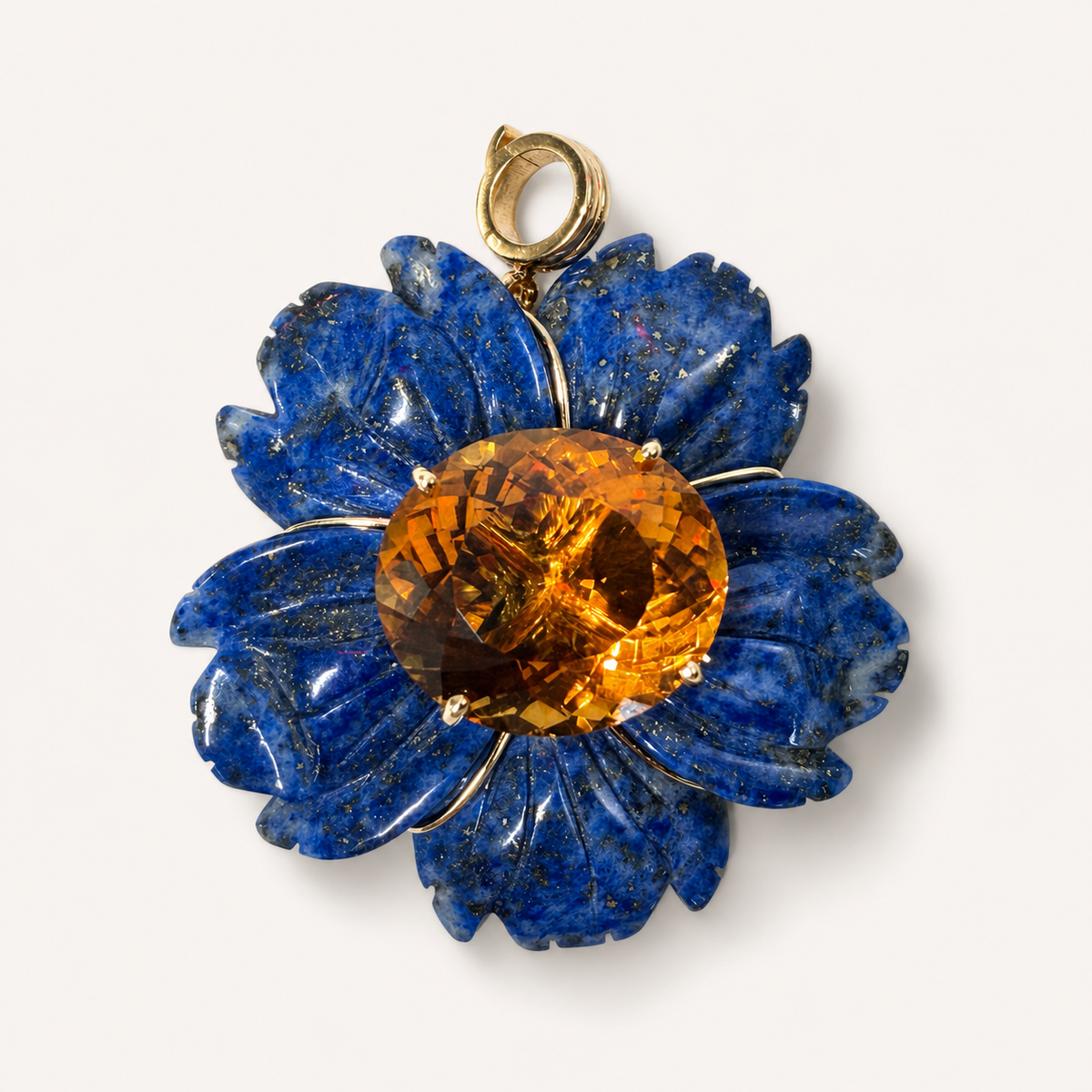 Front view of the Margo pendant, with carved blue lapis lazuli petals, a round golden citrine centre and an 18K gold bail.