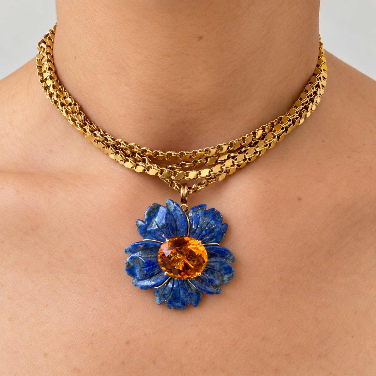 Margo blue lapis lazuli flower pendant with a citrine centre, worn on a gold chain, front view.