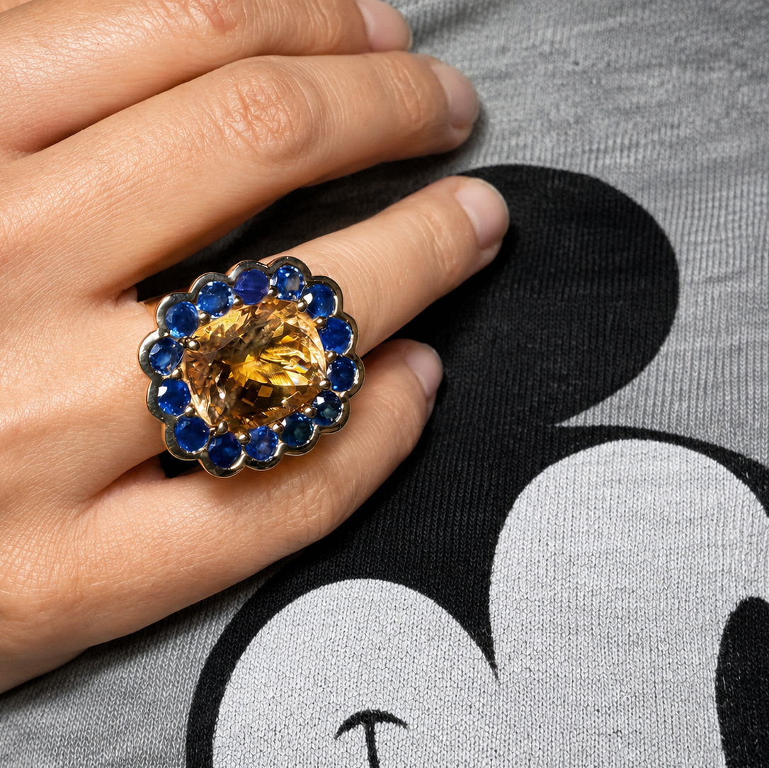 Paloma morganite and blue sapphire cluster ring worn on a hand resting against a grey graphic T-shirt.