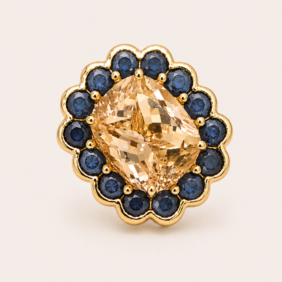 Top view of the Paloma ring, with a cushion-cut morganite surrounded by round blue Ceylon sapphires in a scalloped gold border.