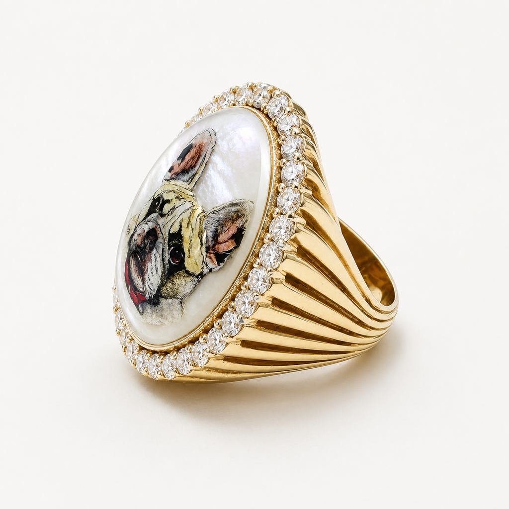 Angled view of the pet portrait ring, with a French bulldog in oval rock crystal, a clear gemstone border and fluted 18K gold shoulders.