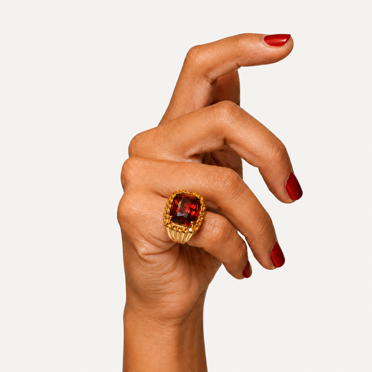 Raj garnet and citrine cluster ring in 18K gold, worn on a hand with red nails.