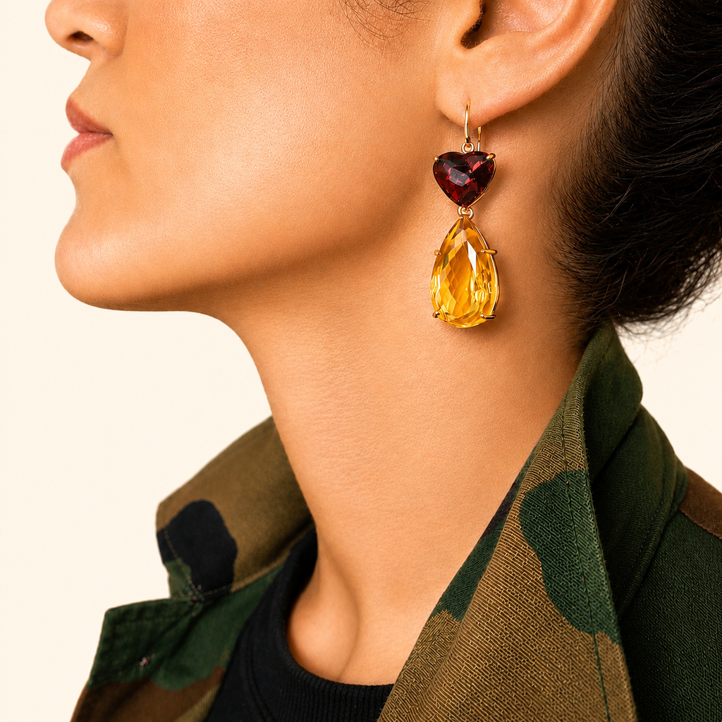 Roubini earring worn on a model, with a deep red heart-shaped garnet above a large pear-shaped golden citrine in 18K gold.