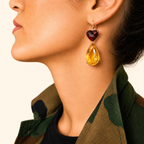 Roubini earring worn on a model, with a deep red heart-shaped garnet above a large pear-shaped golden citrine in 18K gold.