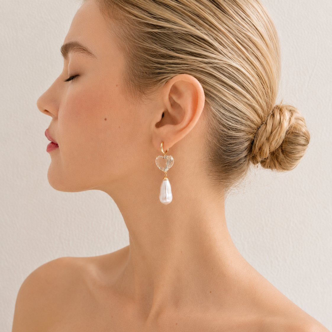 Sandy drop earring worn on a model, with a pale green heart-shaped gemstone and a long freshwater pearl beneath a gold hoop.