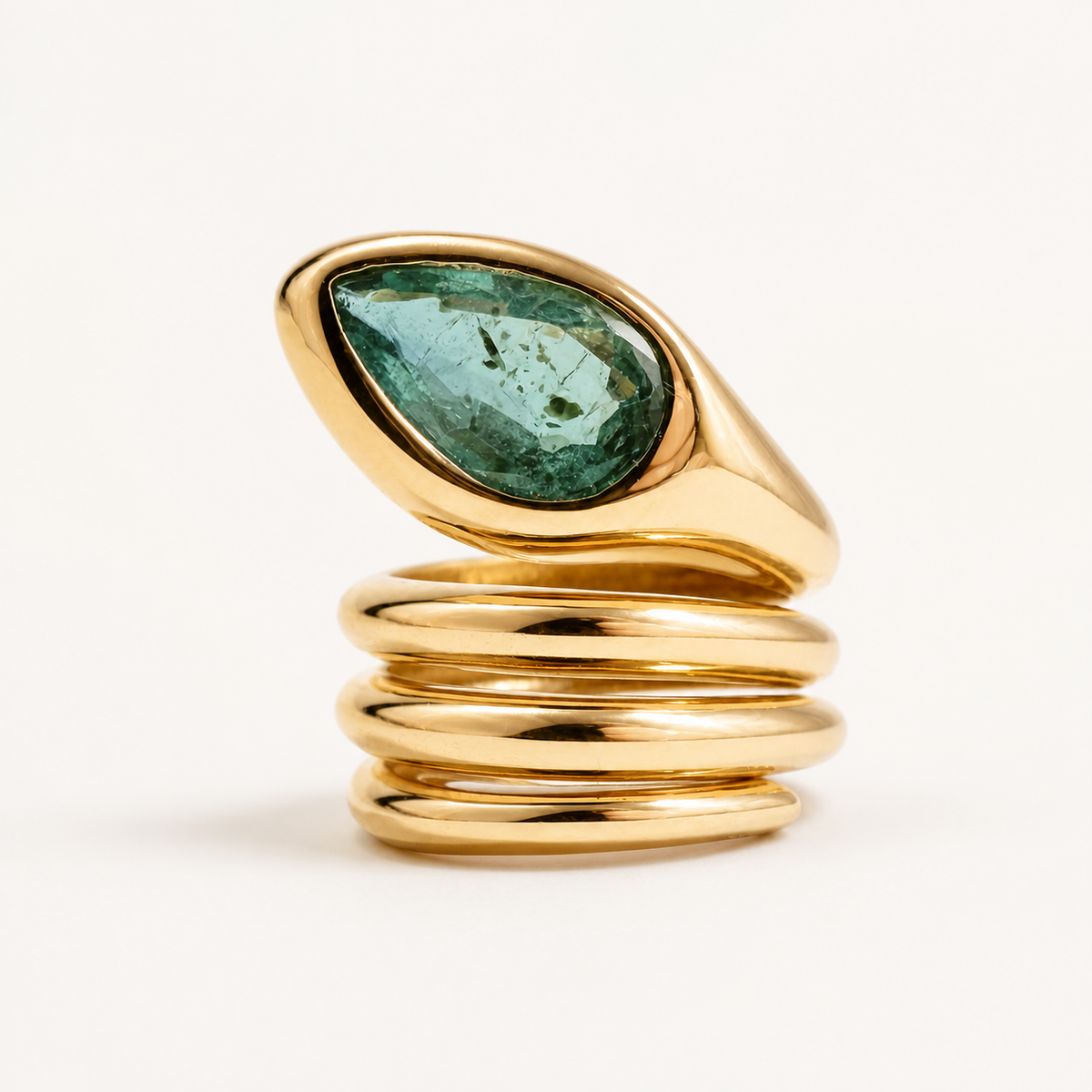 Upright view of the Sylvie snake ring, showing a pear-shaped emerald head above three polished 18K gold coils.