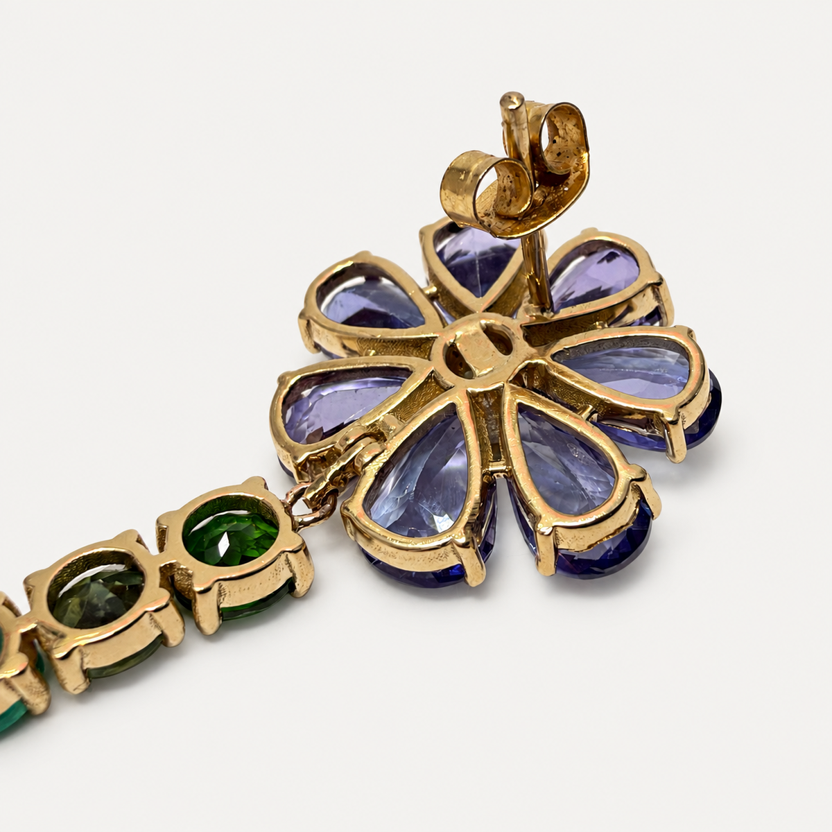 Reverse of the long Violette earring, showing open gold settings behind the tanzanite flower and green stones, with a butterfly fastening.