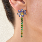 Long Violette earring worn on the ear, with a tanzanite flower, yellow centre and graduated green gemstone drop in 18K gold.